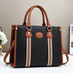 Black and brown striped tote handbag with leather handles, gold hardware, and detachable shoulder strap.