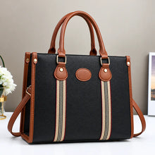 Black and brown striped tote handbag with leather handles, gold hardware, and detachable shoulder strap.
