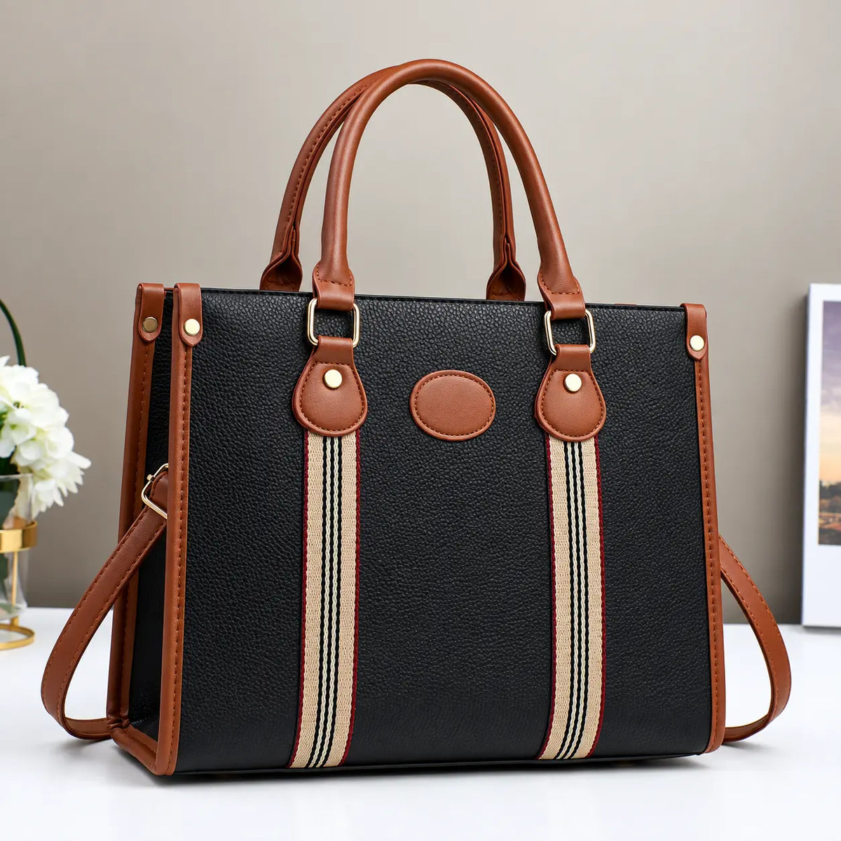 Black and brown striped tote handbag with leather handles, gold hardware, and detachable shoulder strap.