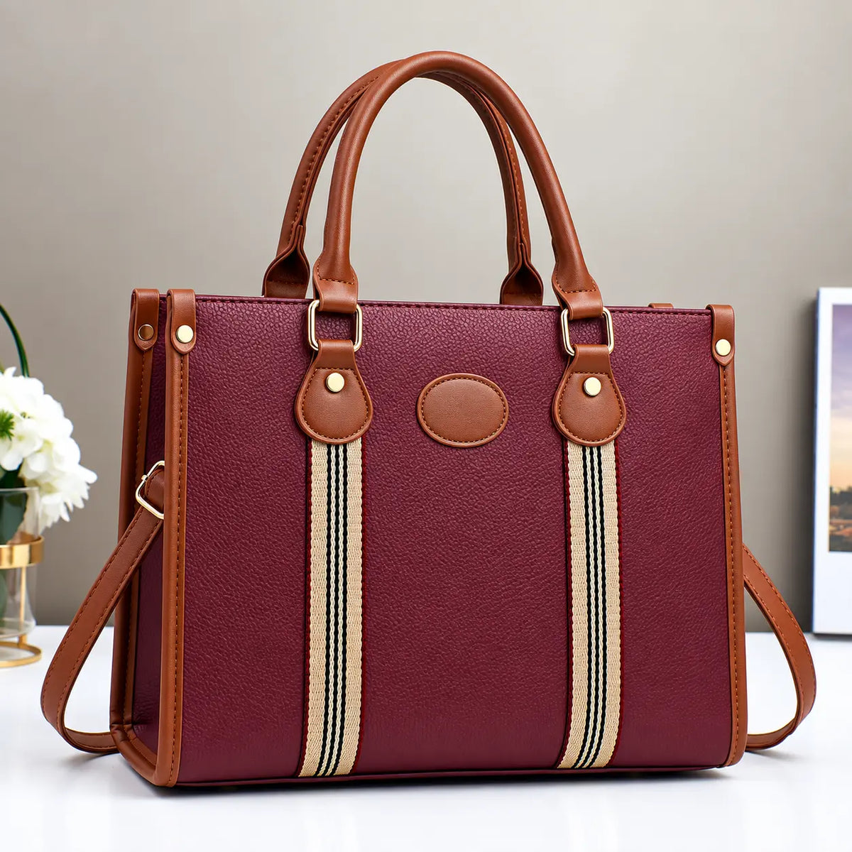 Burgundy and brown striped tote handbag with leather handles, gold hardware, and detachable shoulder strap.