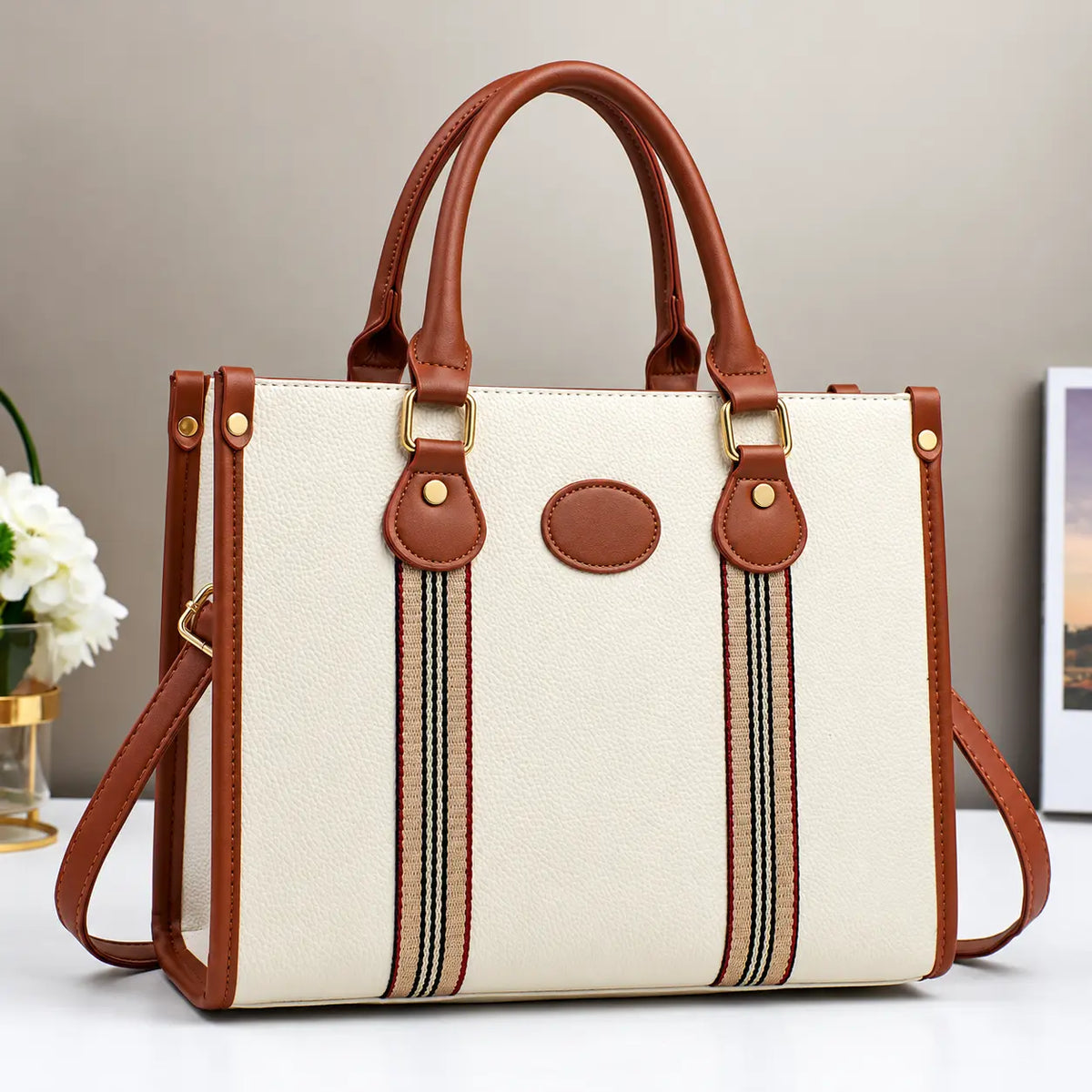 Cream and brown striped tote handbag with leather handles, gold hardware, and detachable shoulder strap.