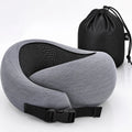 A gray and black travel neck pillow with an adjustable black strap, shown in front of a black drawstring storage bag on a white background.