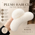 A hand holding a fluffy white faux-fur hair clip against a warm beige promotional background with text highlighting soft hold, lightweight design, and hair-friendly comfort.